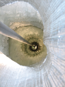A digital optical module sensor is being lowered into a hole in the Antarctic ice. The IceCube detector on the continent consists of 86 strings of sensors, each strung deep down below the surface.